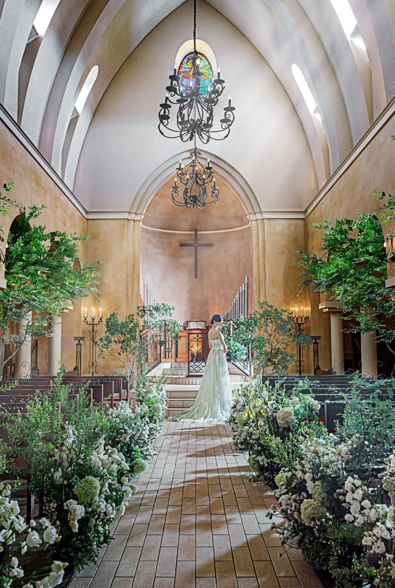 さいたま市の結婚式場アネーリ大宮。まるで森の中のような緑と自然光に包まれた幻想的な大聖堂で、ウェディングドレス姿の花嫁が佇む風景。