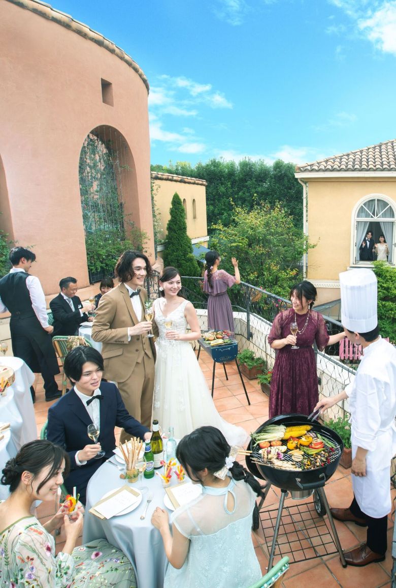 さいたま市の結婚式場アネーリ大宮。南欧風のテラスで行う開放的なガーデンパーティ。シェフのBBQ演出を囲み、ゲストと笑顔で過ごす賑やかなひととき。