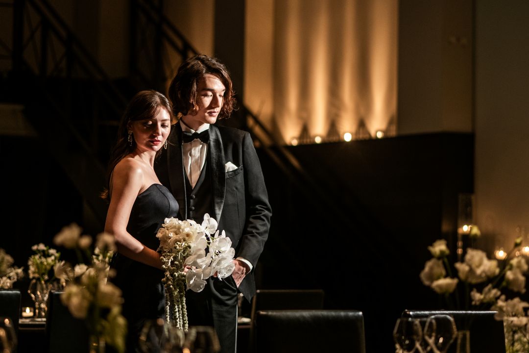 さいたま市の結婚式場アネーリ大宮。黒を基調としたシックな空間で、新郎新婦がポーズ。洗練された雰囲気の中で叶う、大人のナイトパーティ。