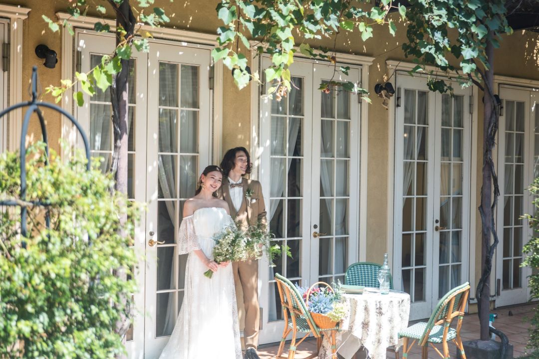 さいたま市の結婚式場アネーリ大宮。緑の蔦と木漏れ日が美しいテラスで、穏やかに微笑む新郎新婦。自然体で過ごせるナチュラルなウェディングフォト。