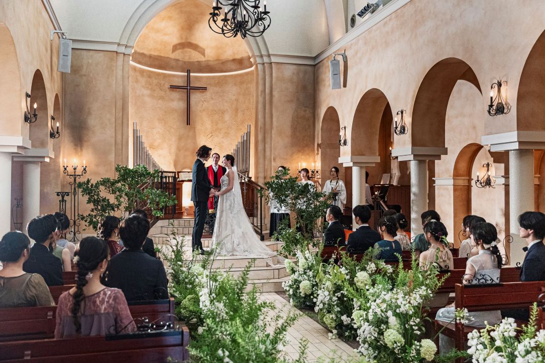 さいたま市の結婚式場アネーリ大宮。緑と花々が彩る大聖堂で、ゲストに見守られ愛を誓う新郎新婦。厳かで温かい空気に包まれた感動のチャペル挙式