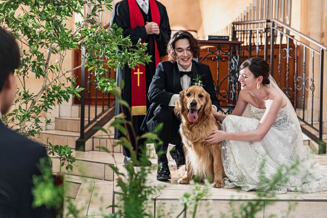 さいたま市の結婚式場アネーリ大宮。チャペルでのペットウェディング。新郎新婦が笑顔で愛犬を撫でる、家族の絆と感動が溢れる挙式シーン。