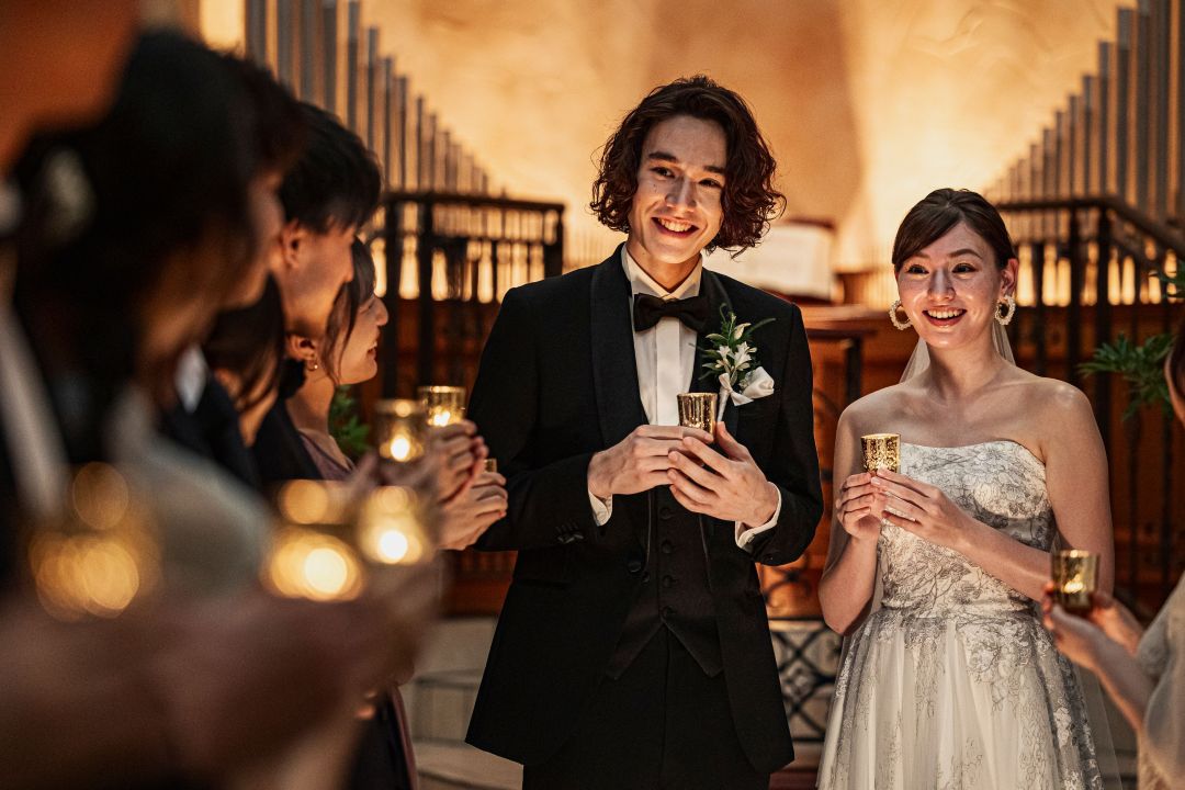 さいたま市の結婚式場アネーリ大宮。ナイトウェディング。幻想的なキャンドルの光に包まれ、笑顔でゲストと歓談する新郎新婦。感動的なチャペルでの一体感。