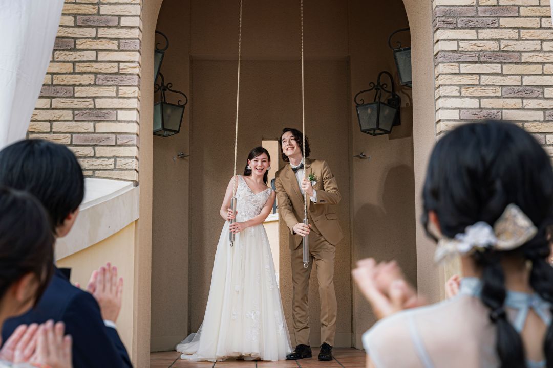 さいたま市の結婚式場アネーリ大宮。ゲストの拍手に包まれ、新郎新婦が教会の鐘を鳴らす。幸せを誓う感動的なアフターセレモニーの瞬間。