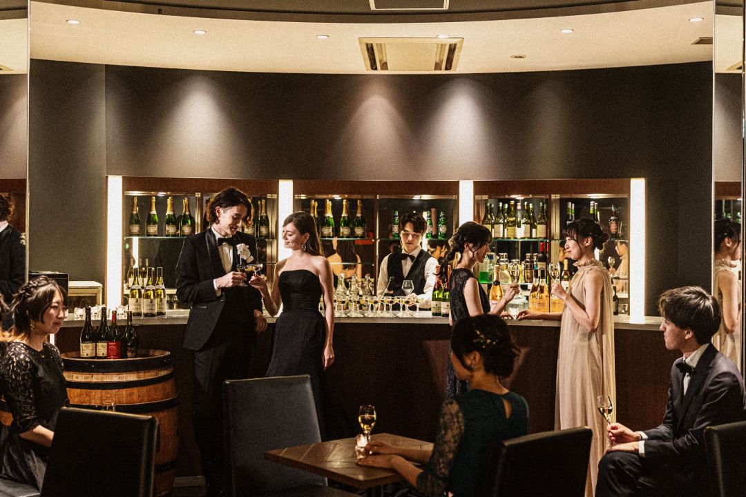 さいたま市の結婚式場アネーリ大宮。シックなバーカウンターでカクテルを片手に語らう新郎新婦。ゲストと共に楽しむ、大人のナイトウェディング。