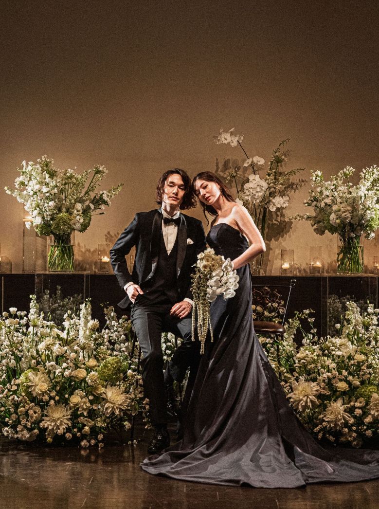 さいたま市の結婚式場アネーリ大宮。白と緑の装花が彩るシックな会場で、ブラックドレスの花嫁と新郎がポーズ。洗練された大人のウェディングフォト