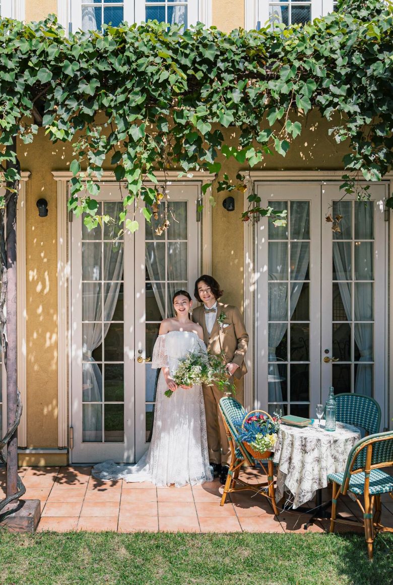 さいたま市の結婚式場アネーリ大宮。緑の蔦と木漏れ日が美しいテラスで、穏やかに微笑む新郎新婦。自然体で過ごせるナチュラルなウェディングフォト。