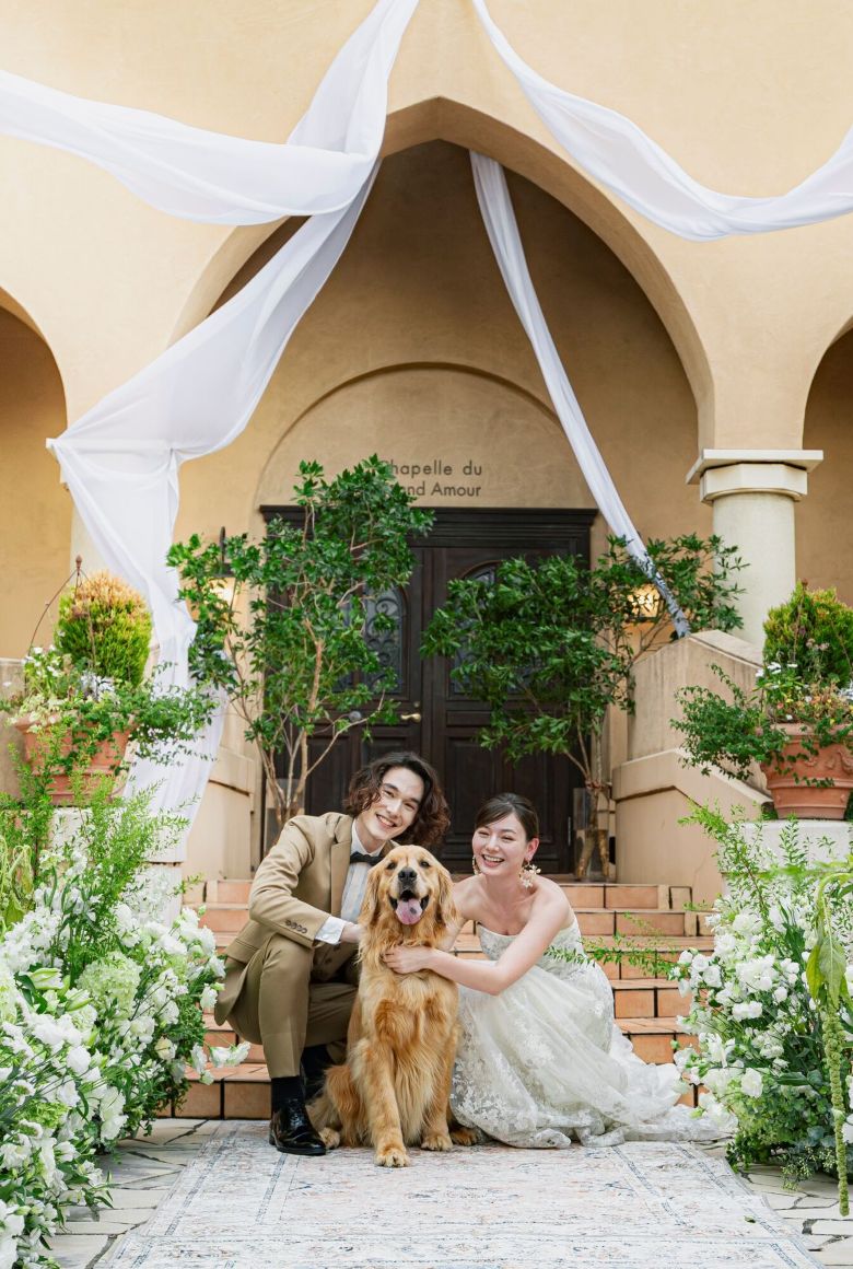 さいたま市の結婚式場アネーリ大宮。緑豊かなガーデンで、愛犬と一緒に笑顔を見せる新郎新婦。大切なペットも家族として参加できるアットホームな挙式。