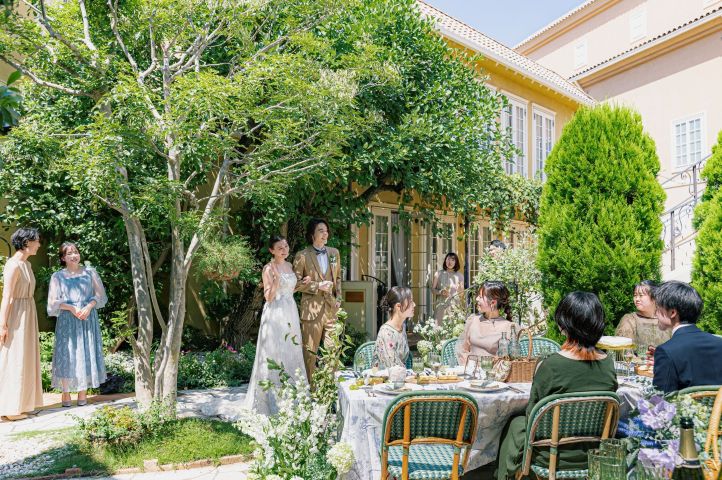 アネーリ大宮の緑豊かなガーデンで、ゲストの笑顔に囲まれて過ごす新郎新婦。さいたま市で叶う、ヨーロッパ風の邸宅を貸し切った開放感あふれるナチュラルなガーデンウェディングのパーティーシーン。