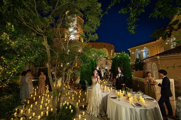 無数のキャンドルが足元を照らすアネーリ大宮のナイトガーデンパーティー。さいたま市の結婚式場でゲストと楽しむ、幻想的なイルミネーションとロマンチックなナイトウェディングの演出シーン。