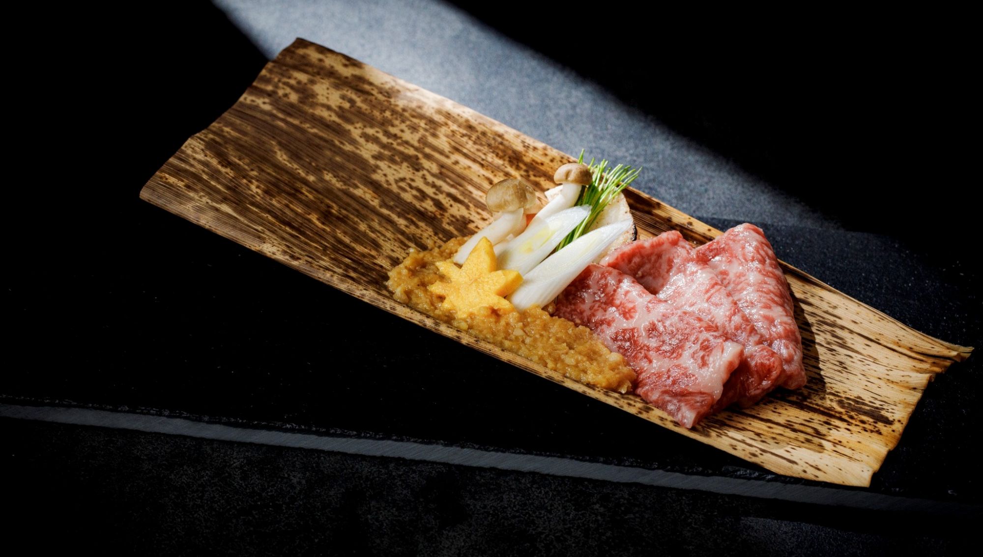 アネーリ大宮の婚礼料理。朴葉の上に美しく並べられた霜降り和牛と、紅葉のあしらいを添えた旬の野菜。大宮の結婚式場で提供される、和の趣と高級感あふれるコース料理の一皿。