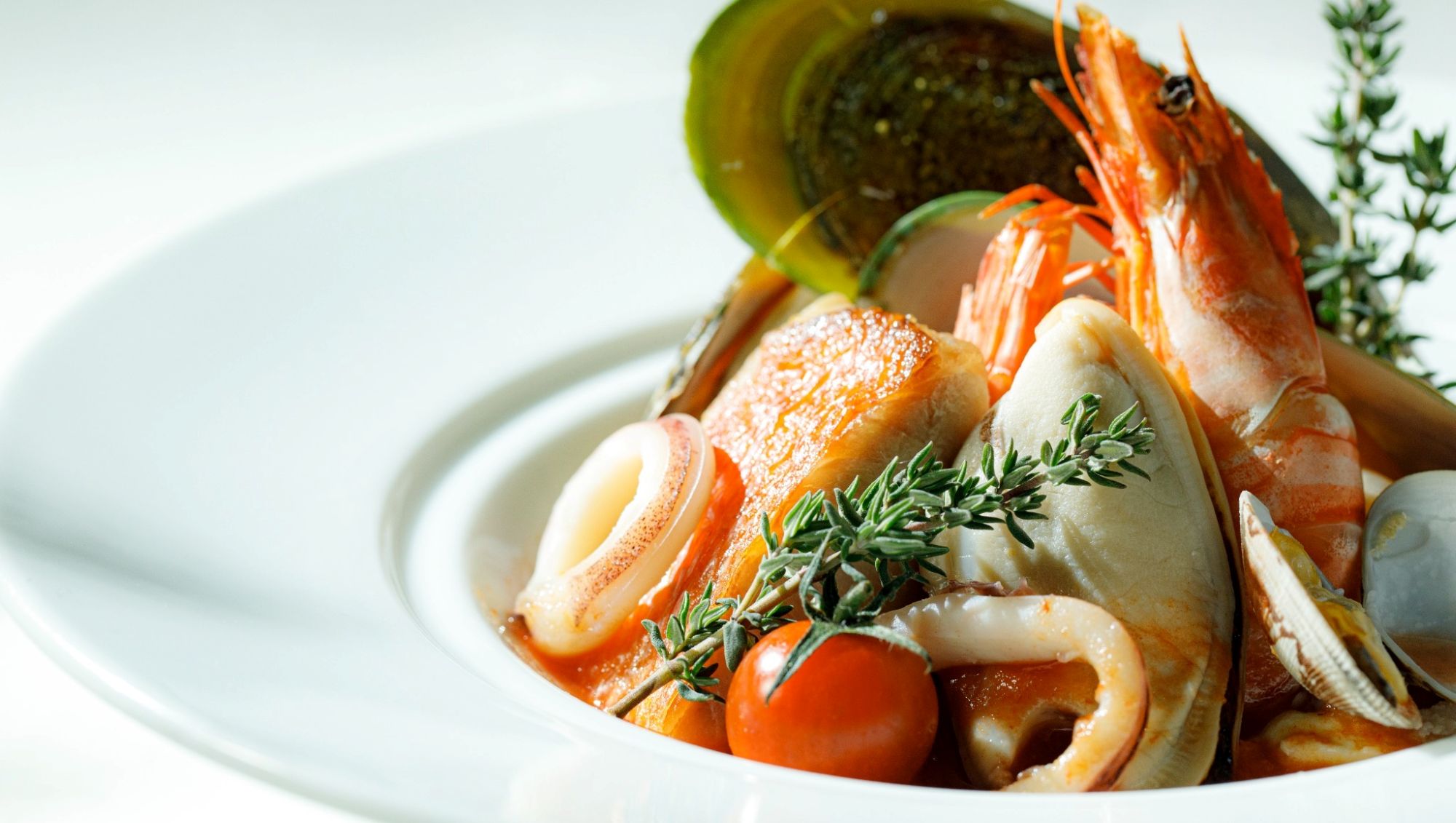 アネーリ大宮の婚礼料理。白い深皿に盛り付けられた有頭海老やムール貝、白身魚の贅沢なブイヤベース風の一品。大宮の結婚式場でゲストに振る舞われる、海の幸の旨みが凝縮された本格フレンチの魚料理。